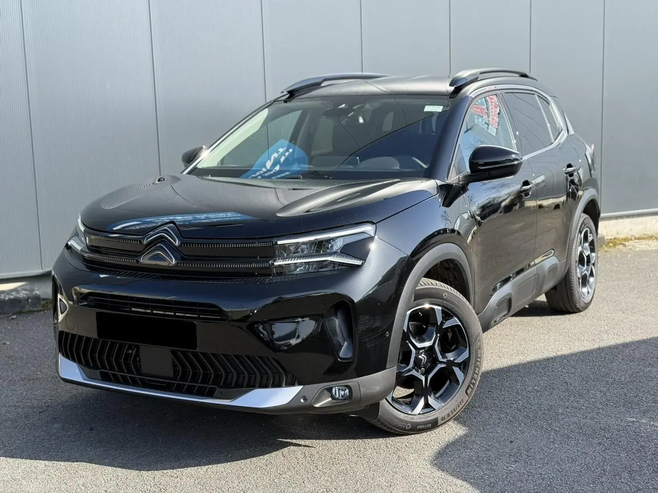 Vue 3/4 avant d'un Citroën C5 Aircross 2025 noir Perla avec jantes alliage bi-ton et barres de toit noires.