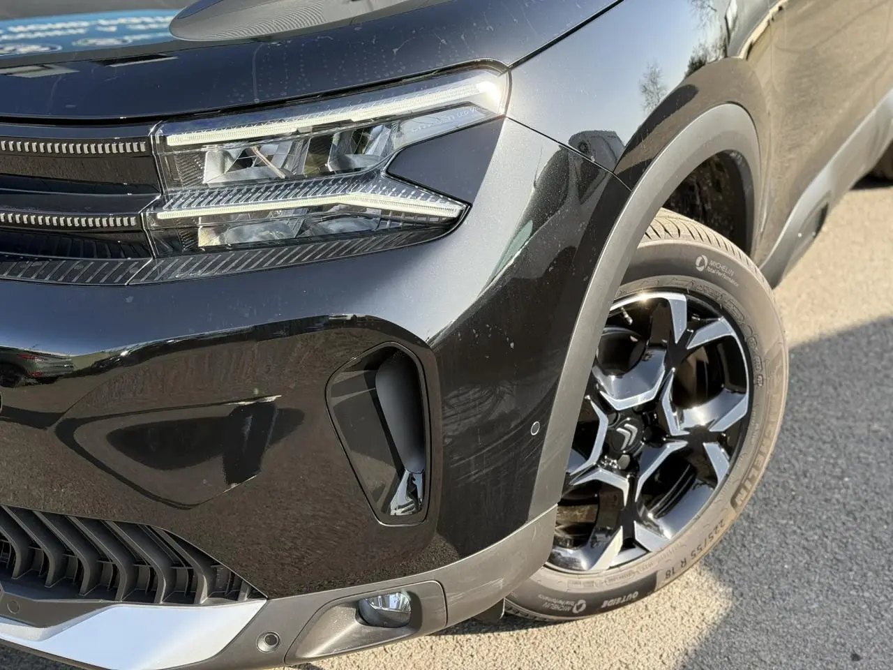 Gros plan sur l’avant droit noir Perla du Citroën C5 Aircross 2025, mettant en valeur le phare LED et la jante alliage 18 pouces.