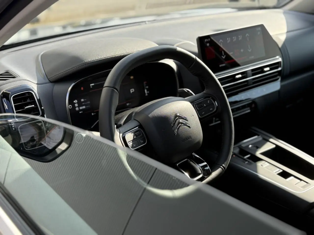 Vue intérieure côté conducteur du Citroën C5 Aircross 2025, volant cuir et tableau de bord avec écran tactile.