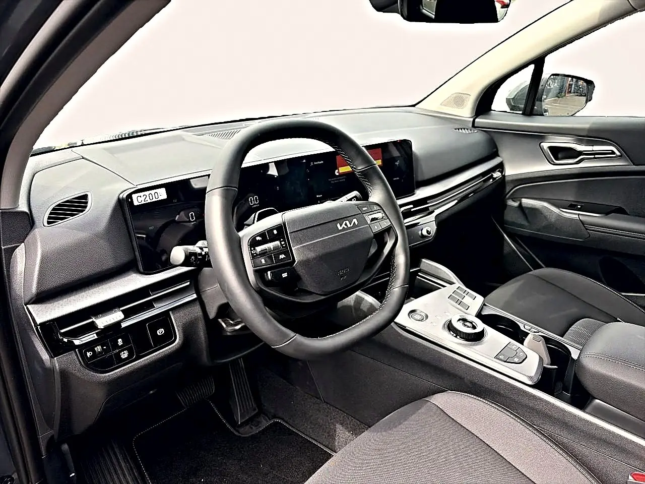 Intérieur du Kia Sportage 1.6 hybride 239 gris eclipse, vue côté conducteur sur le tableau de bord et volant multifonction cuir.