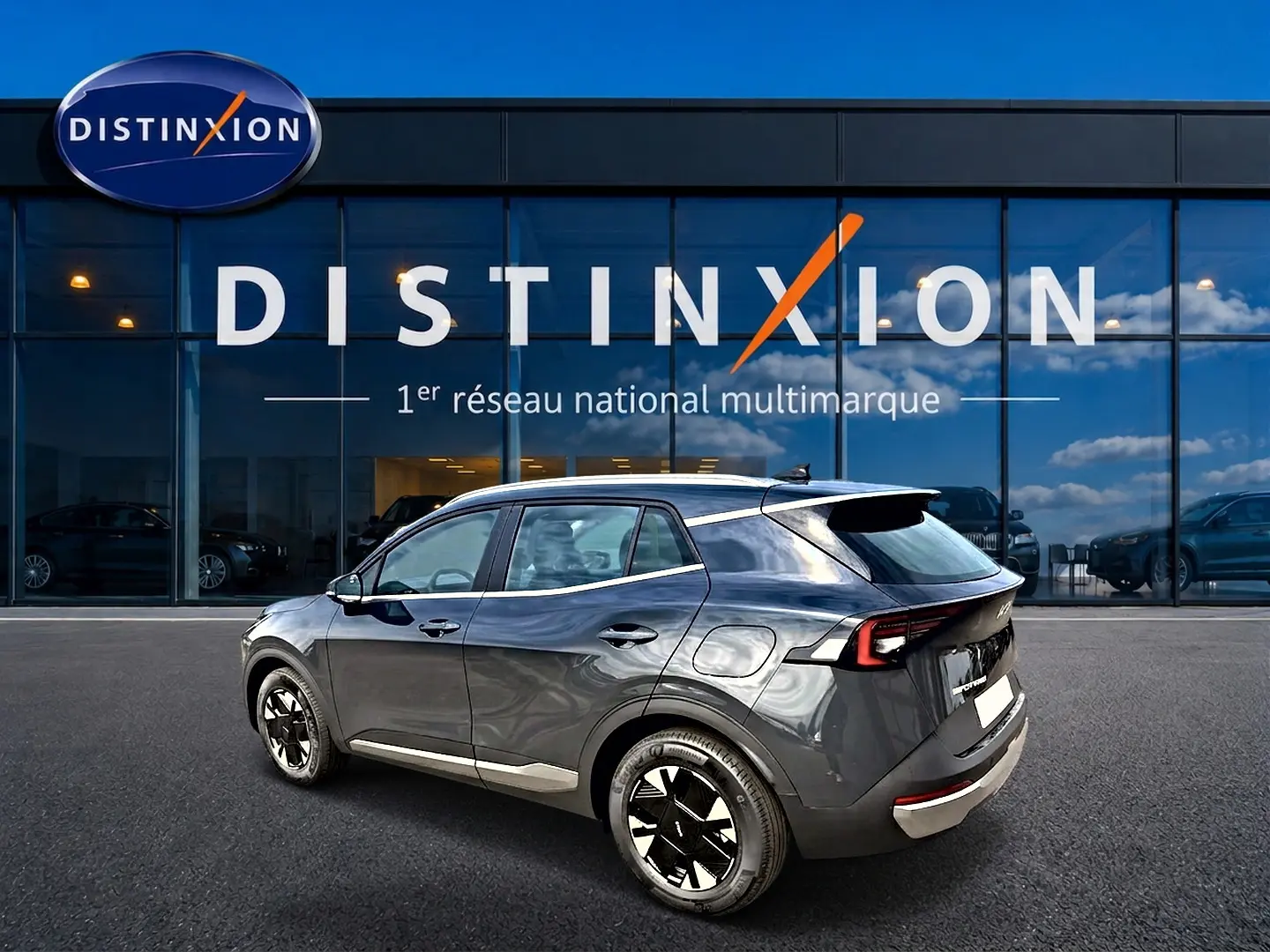 KIA Sportage 1.6 hybride gris eclipse en 3/4 arrière droit, avec jantes alu noires et feux arrière LED distinctifs.