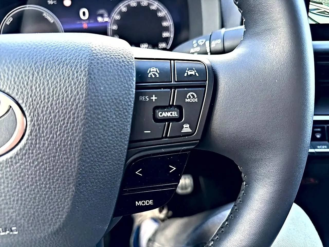 Gros plan sur le volant multifonction noir du Toyota C-HR gris, avec commandes de régulateur et assistance visibles.