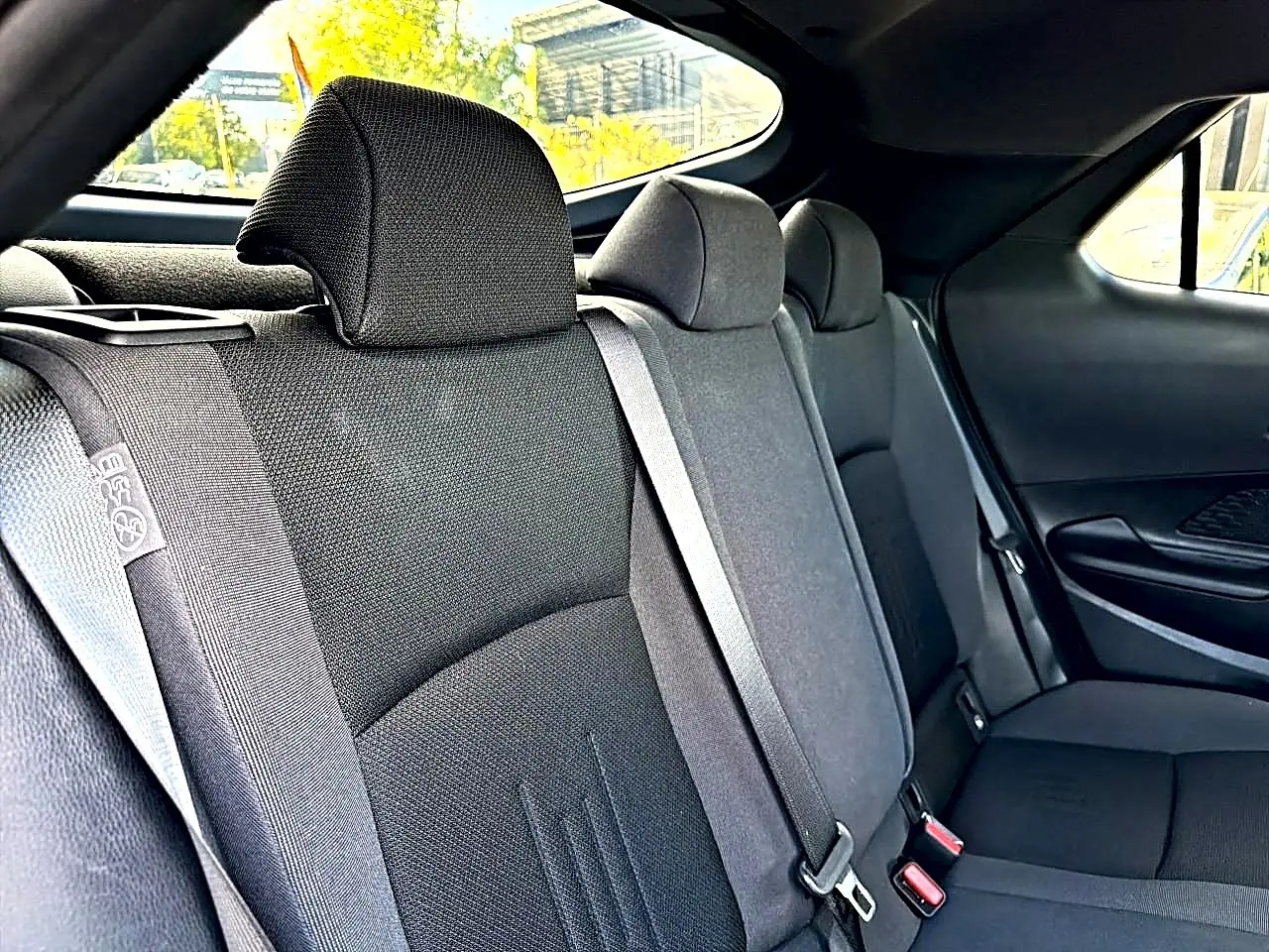 Vue intérieure côté droit des sièges arrière gris foncé du Toyota C-HR 1.8 hybride 2025 avec ceintures de sécurité visibles.