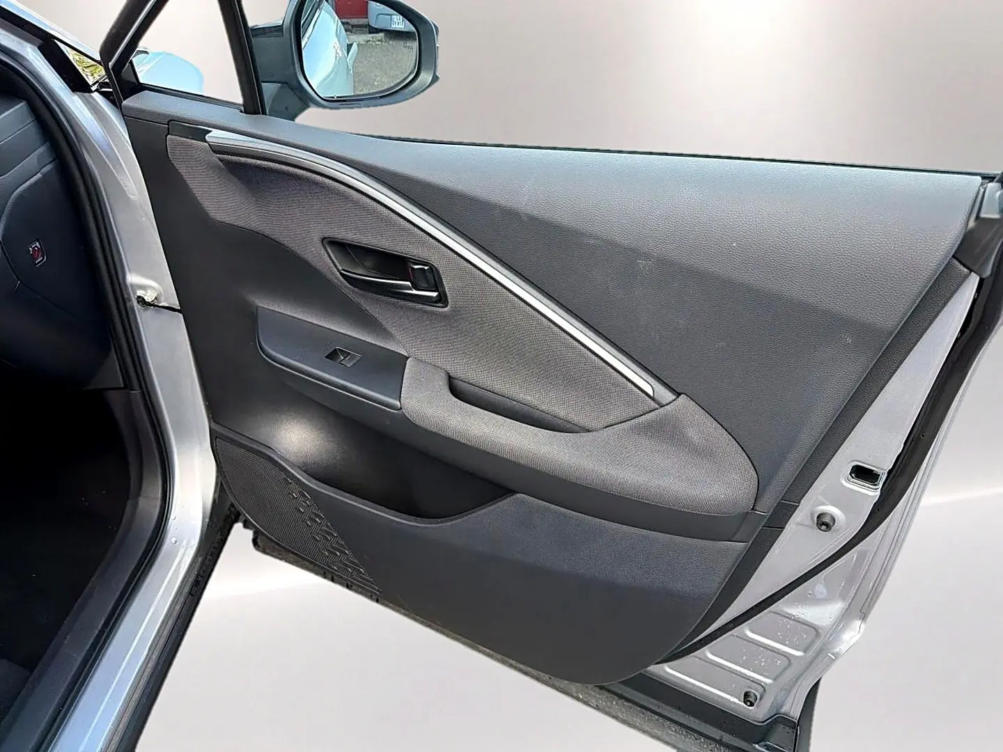 Vue intérieure de la porte avant gauche gris foncé du Toyota C-HR 1.8 hybride 2025 avec poignée et commande de vitre.