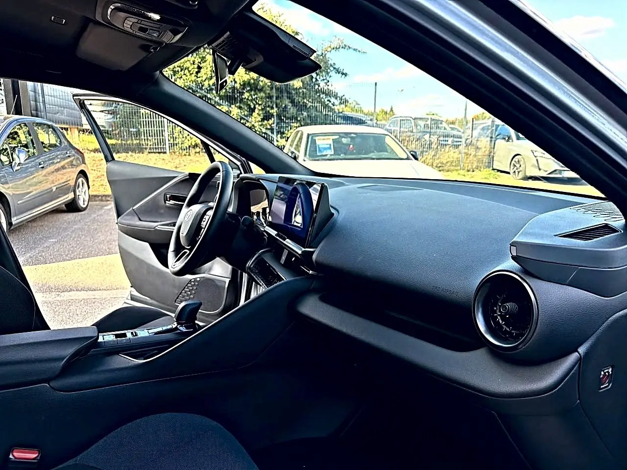 Intérieur avant droit du Toyota C-HR gris 2025, tableau de bord moderne avec écran tactile et volant multifonction.