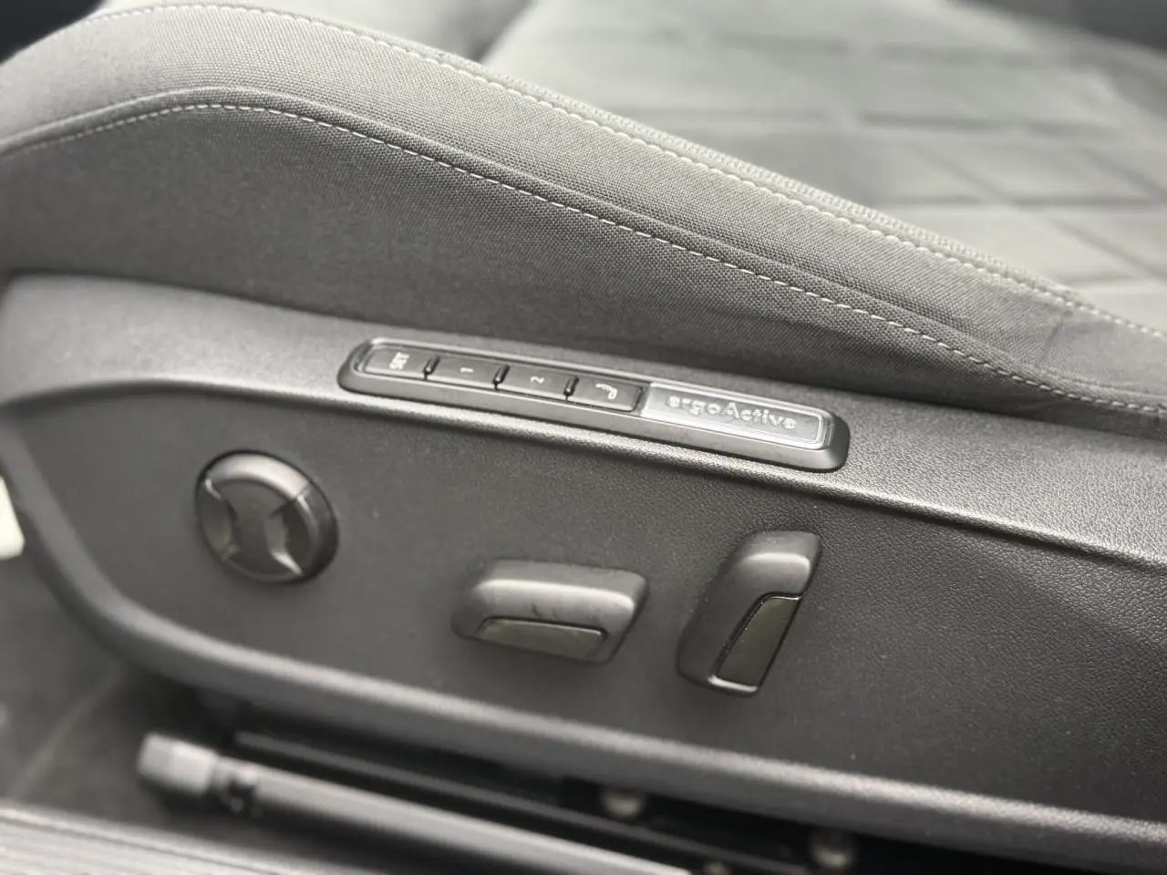 Gros plan sur les commandes électriques du siège ergoActive côté conducteur d'une Volkswagen Golf VIII Deep Black 2024.