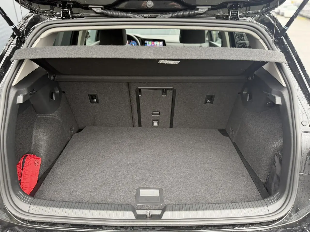 Coffre ouvert vue arrière d’une Volkswagen Golf VIII Deep Black 2024, avec cache-bagages et intérieur gris.