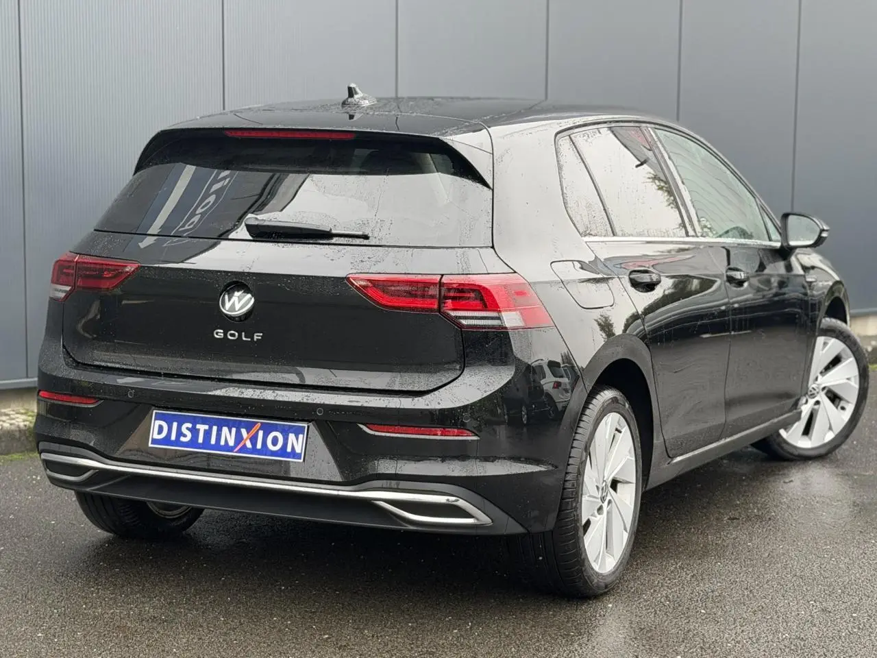 Vue 3/4 arrière droite d'une Volkswagen Golf VIII Deep Black avec feux arrière LED et jantes alliage 17 pouces.
