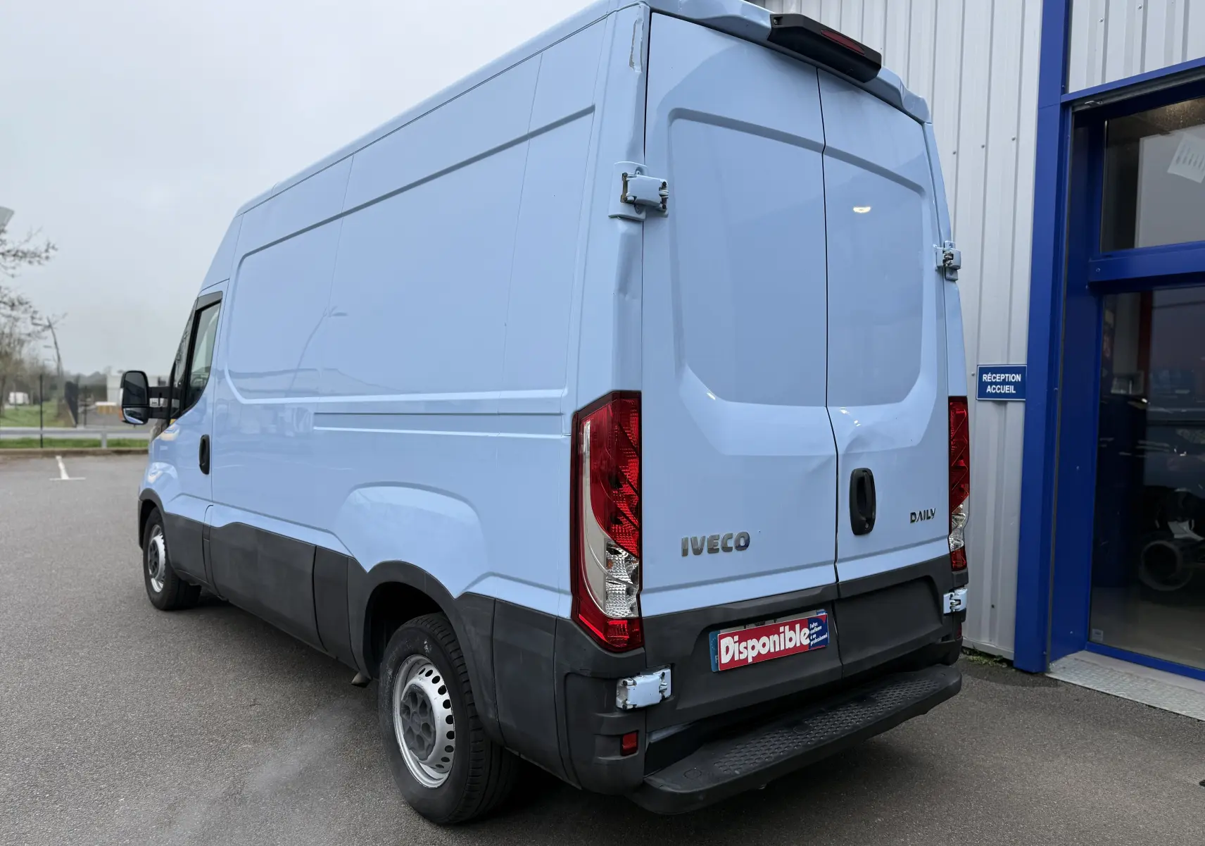 Vue 3/4 arrière droite d’un fourgon Iveco Daily bleu clair 2017 avec portes arrière fermées et pare-chocs noir.