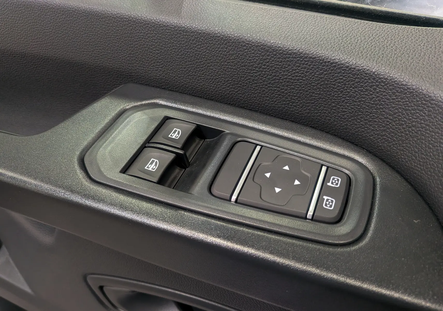 Panneau de commandes des vitres et rétroviseurs électriques sur la portière côté gauche d'un Renault Trafic blanc 2023.