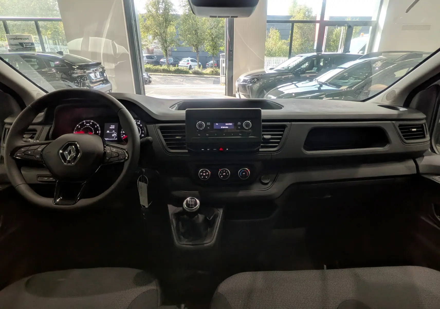 Vue intérieure avant du Renault Trafic Cabine Approfondie blanc minéral 2023, avec tableau de bord et volant multifonction.