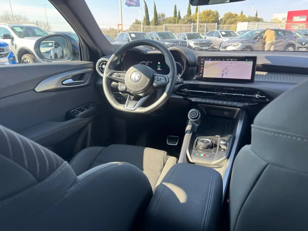 Vue intérieure de l'Alfa Romeo Tonale 2025, tableau de bord et volant sport avec écran tactile et console centrale moderne.