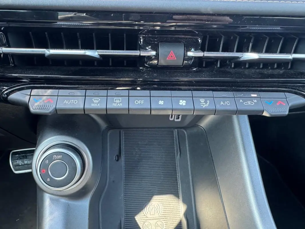 Vue rapprochée de la console centrale de l'Alfa Romeo Tonale bleu foncé, montrant les commandes de climatisation et le chargeur sans fil.