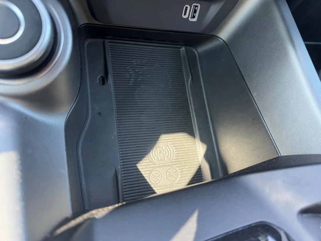 Gros plan sur la console centrale noire de l'Alfa Romeo Tonale 2025, avec zone de charge sans fil et ports USB visibles.