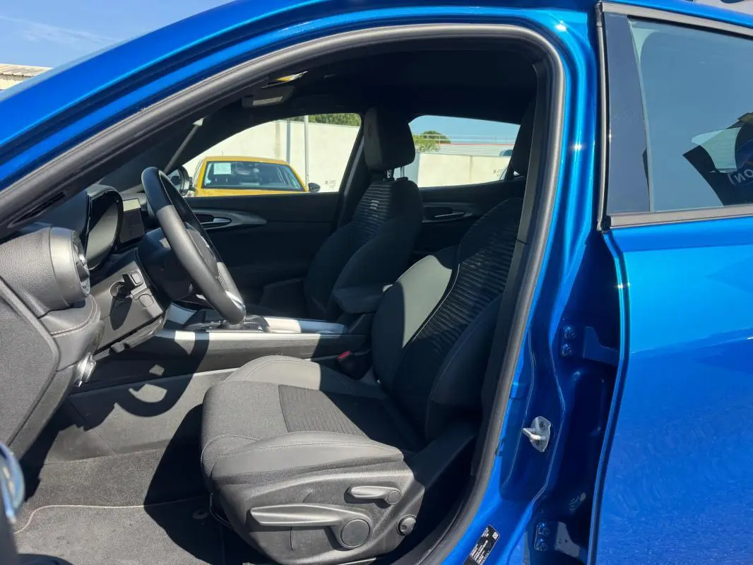 Vue intérieure côté conducteur de l'Alfa Romeo Tonale bleu foncé 2025, avec sièges sport et volant multifonction.