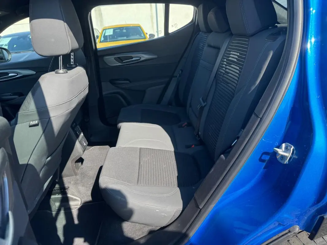 Vue intérieure arrière côté droit de l'Alfa Romeo Tonale bleu foncé, montrant les sièges arrière en tissu noir et détails de la porte ouverte.