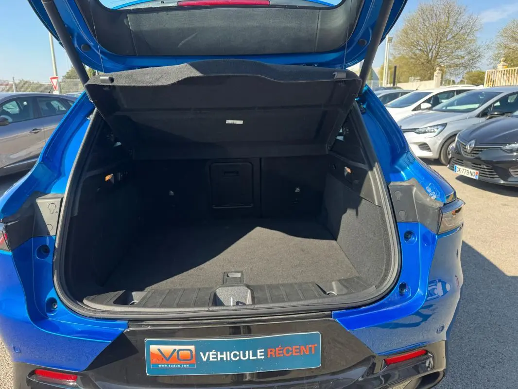 Coffre ouvert vu de l’arrière d’un Alfa Romeo Tonale bleu foncé, avec hayon relevé et intérieur spacieux.