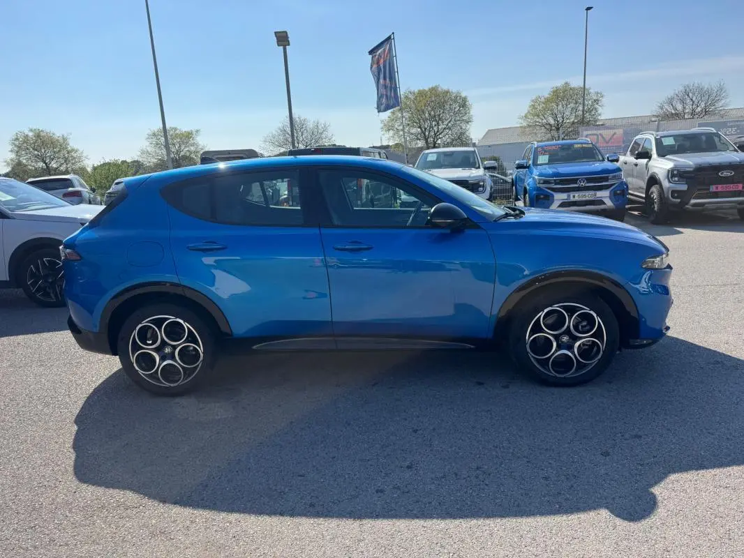 Vue de profil côté gauche d'une Alfa Romeo Tonale bleu foncé avec jantes alliage 18 pouces sur parking.