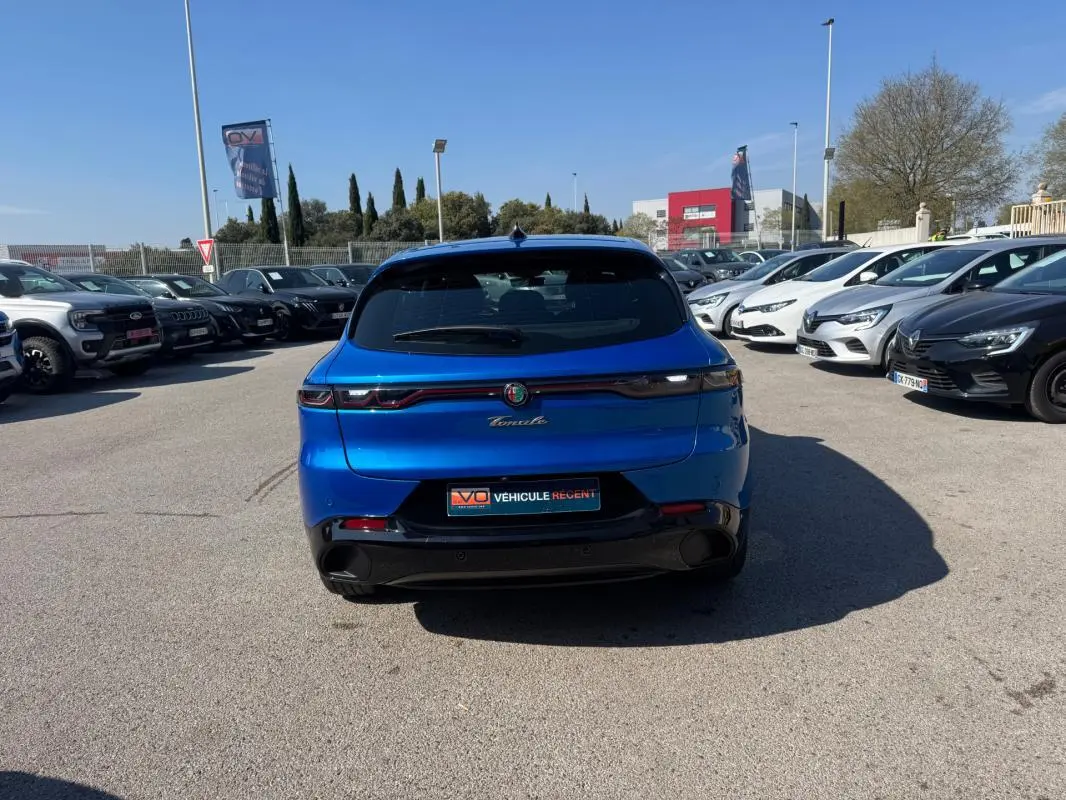 Vue arrière d'une Alfa Romeo Tonale bleu foncé 2025, avec feux arrière fins et jantes alliage visibles en concession.