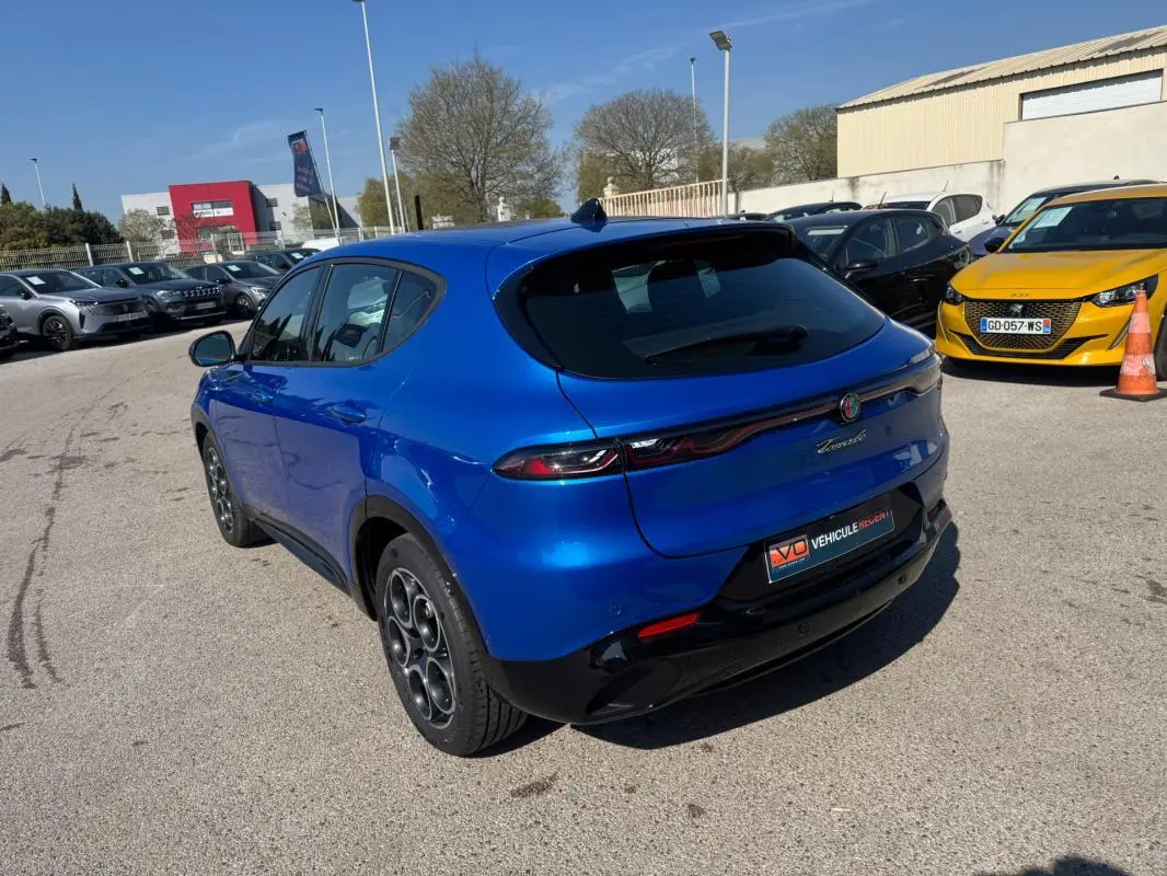 Vue 3/4 arrière gauche de l'Alfa Romeo Tonale bleu foncé avec jantes alliage 18 pouces sur parking extérieur.