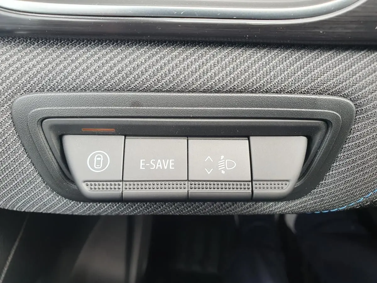 Gros plan sur les boutons de commande E-SAVE et réglage des phares dans l’habitacle du Renault Captur bleu Iron.