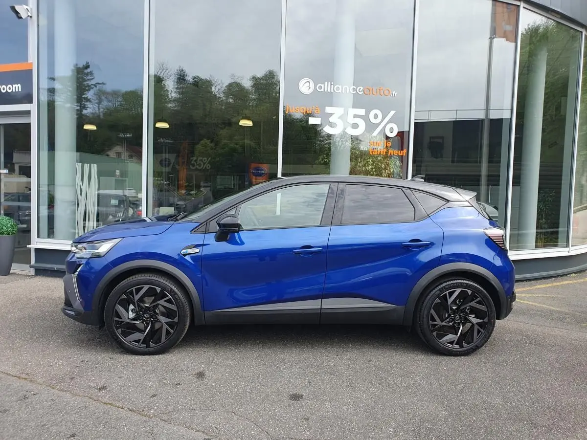Profil droit d’un Renault Captur 2026 bleu Iron avec jantes noires et toit noir devant une vitrine.