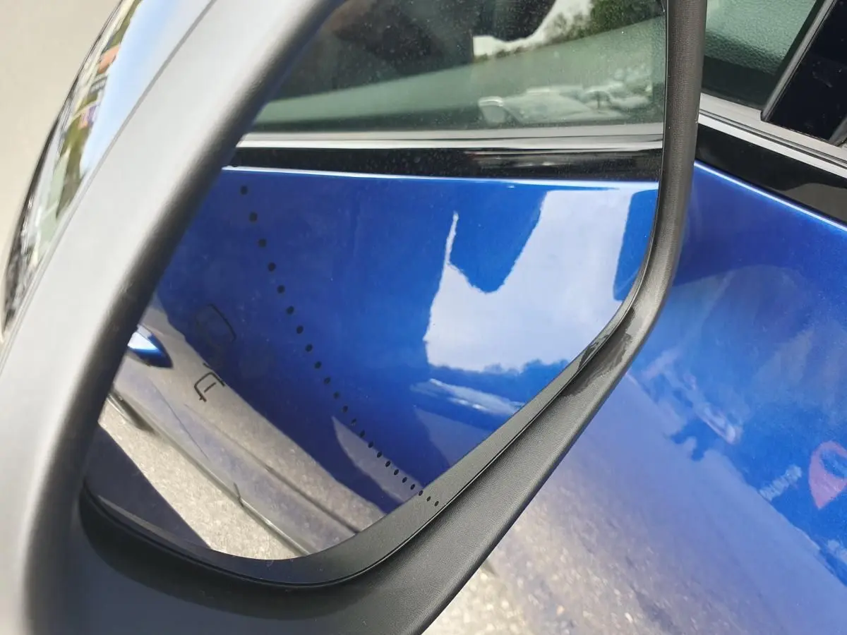 Gros plan sur le rétroviseur côté droit d’un Renault Captur bleu Iron avec reflet de la carrosserie métallique.