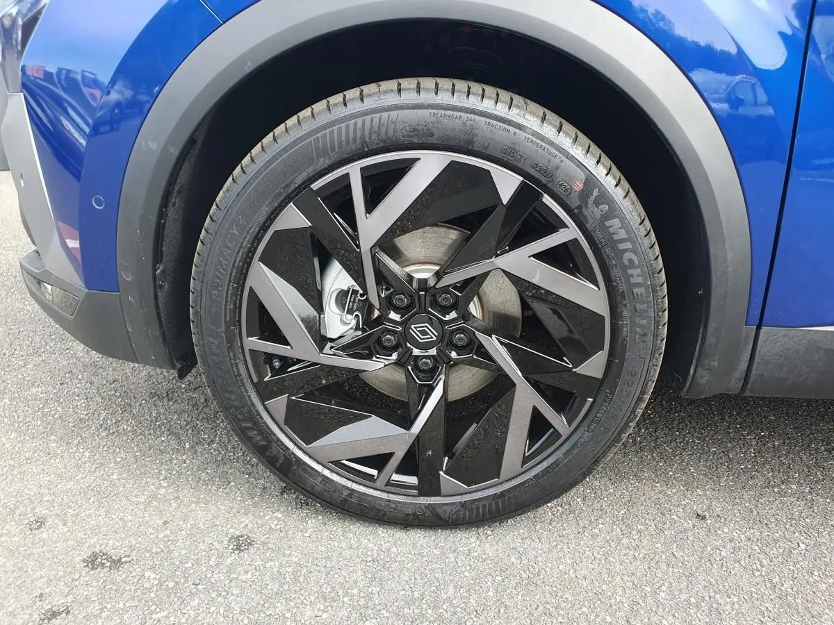 Gros plan sur la jante aluminium 19 pouces Elixir noire et argent du Renault Captur bleu Iron, côté arrière droit.