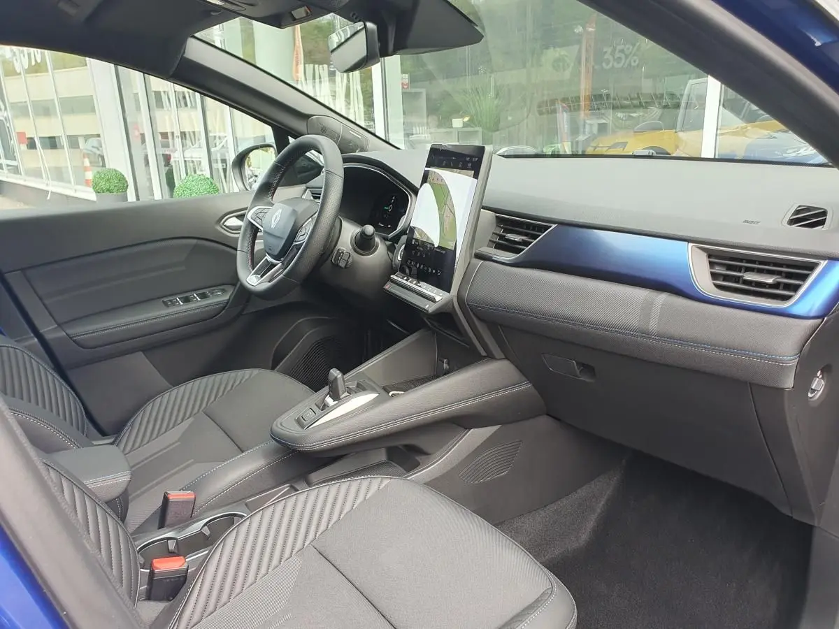 Intérieur avant droit du Renault Captur bleu Iron 2026, avec tableau de bord numérique et écran tactile vertical.