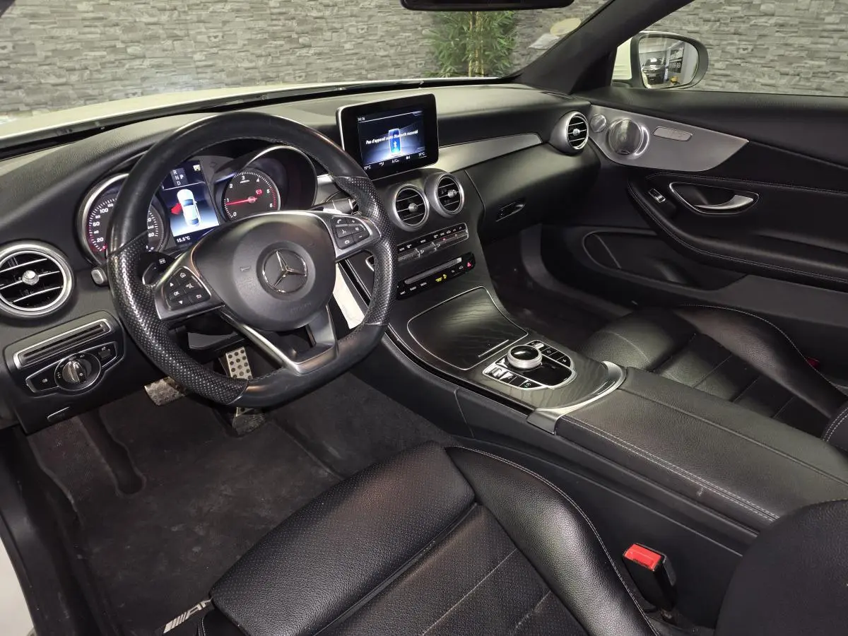 Vue intérieure côté conducteur de la Mercedes Classe C Coupé 2017, avec tableau de bord noir et volant sport AMG.