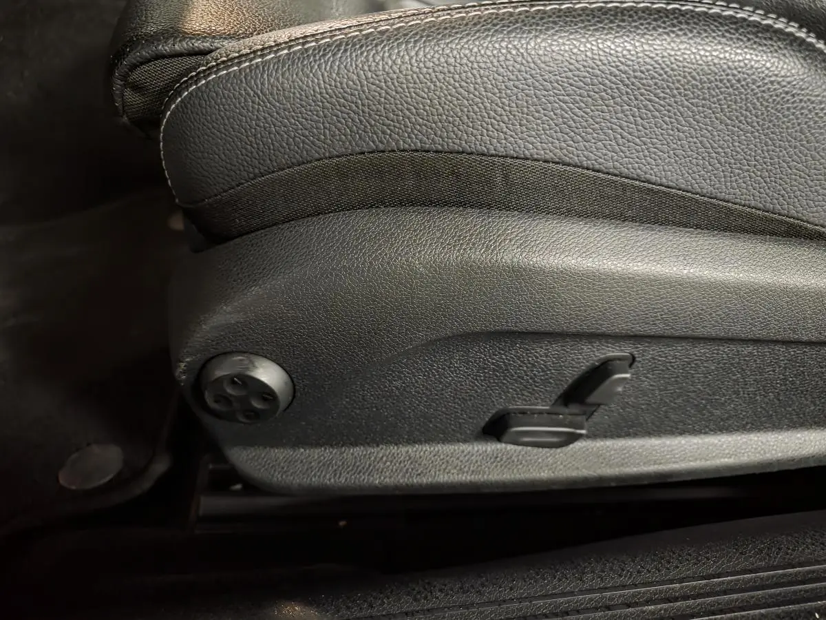 Détail du côté gauche d’un siège avant noir en cuir avec commandes électriques sur une Mercedes Classe C Coupé blanc.