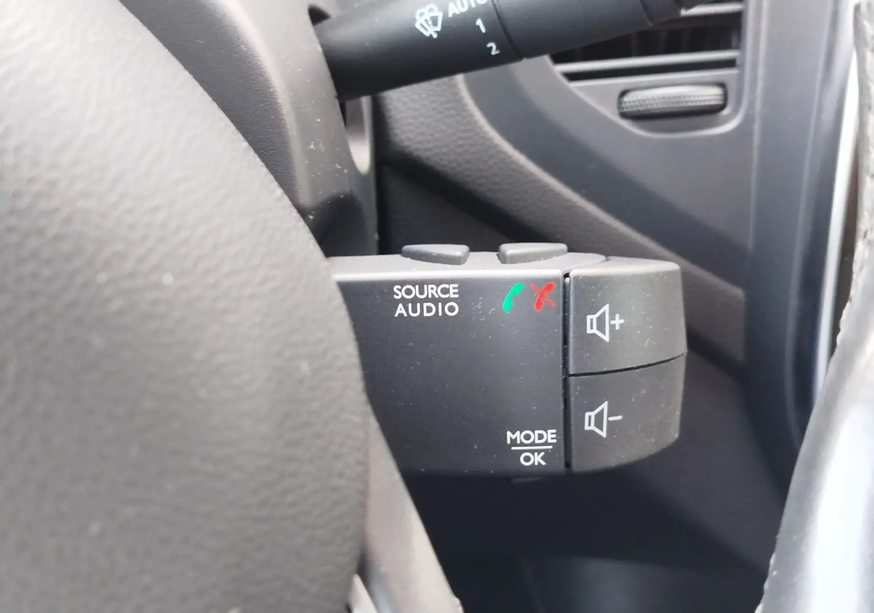 Gros plan sur les commandes audio au volant du Renault Captur gris Cassiopée, avec boutons de volume et gestion d'appels.