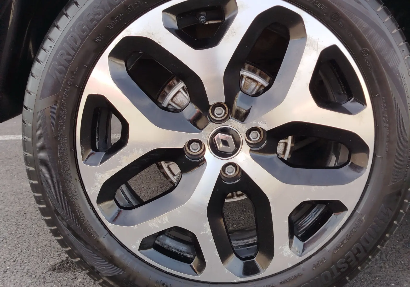 Gros plan sur la jante alliage bicolore noire et argent avec logo Renault au centre du Renault Captur Gris Cassiopée.