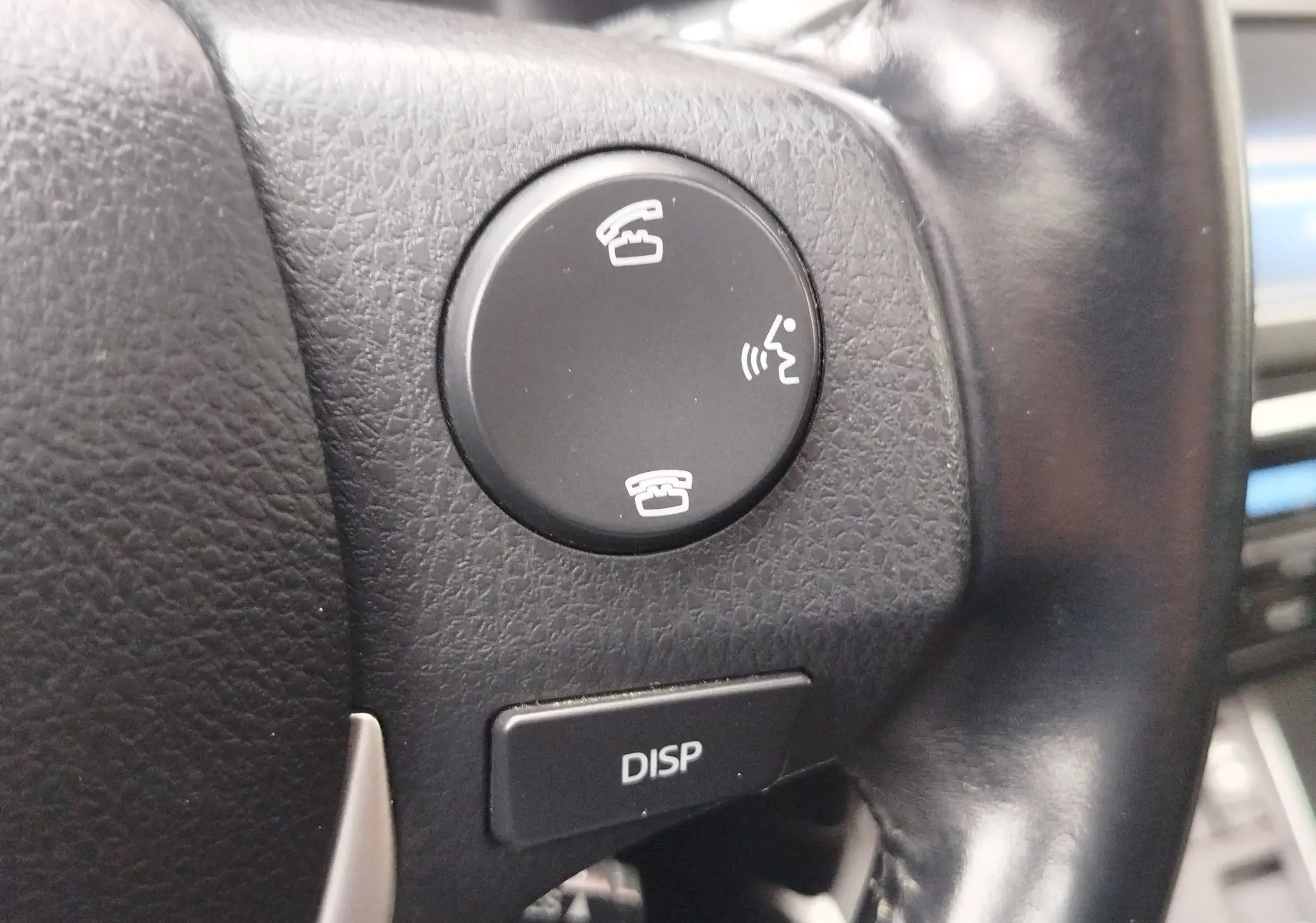 Gros plan sur les boutons de commande d’appel et affichage au volant en cuir noir d’une Toyota Auris HSD 136h gris aluminium.