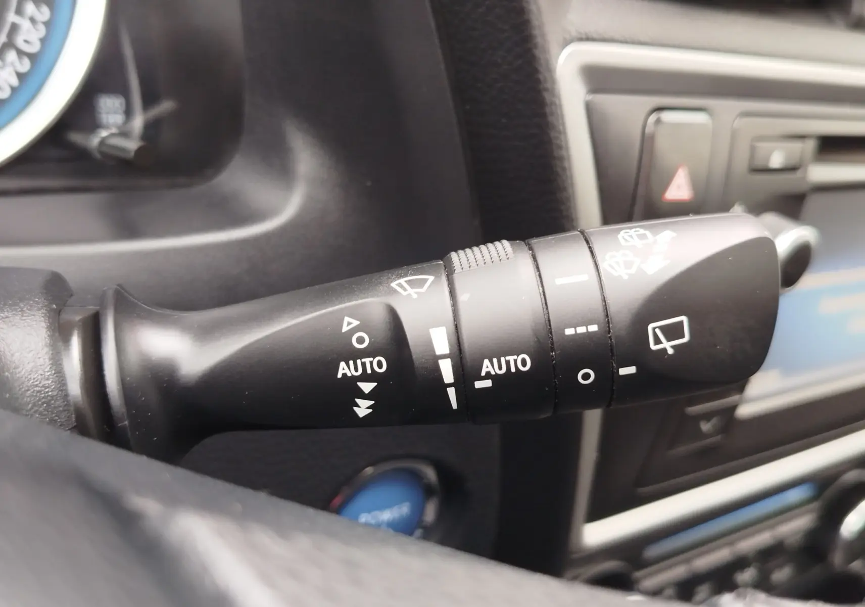 Gros plan sur la commande des essuie-glaces dans l’habitacle d’une Toyota Auris HSD 136h gris aluminium de 2015.