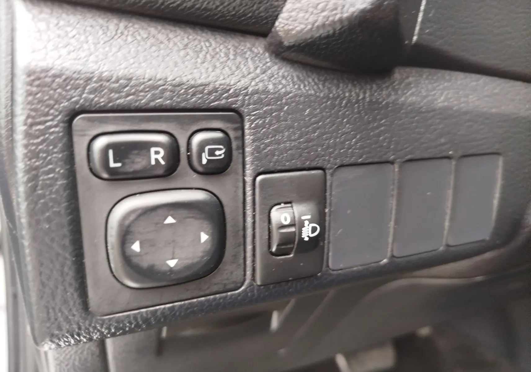 Gros plan sur les commandes de réglage des rétroviseurs et de l’éclairage, intérieur noir de la Toyota Auris HSD 136h 2015.
