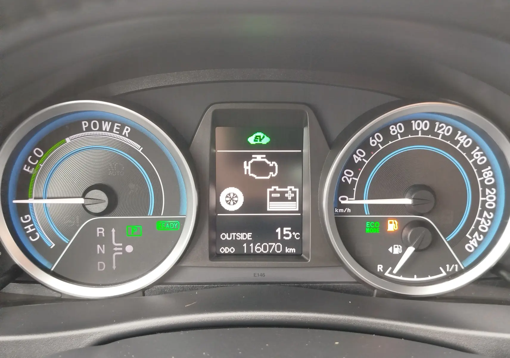 Tableau de bord de Toyota Auris HSD 136h gris, affichant 116070 km, mode ECO et température extérieure à 15°C.