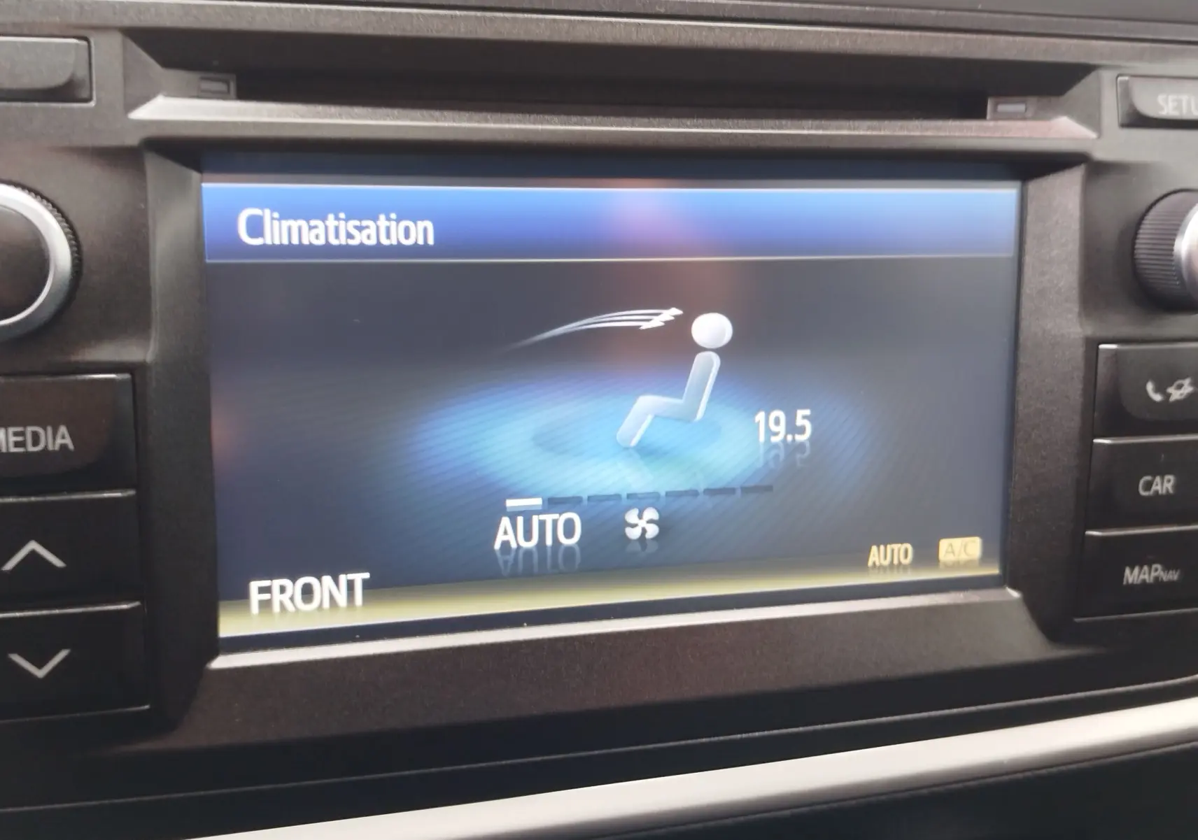 Écran central de la Toyota Auris HSD 136h gris aluminium montrant le réglage automatique de la climatisation à 19,5°C.