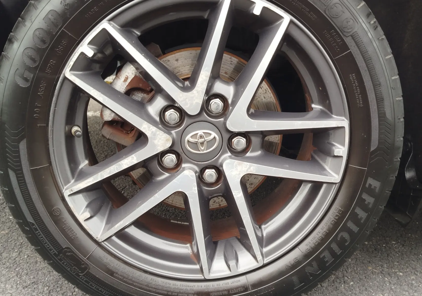 Gros plan sur la jante alliage gris foncé avec logo Toyota au centre, pneu Goodyear Efficient Grip visible.