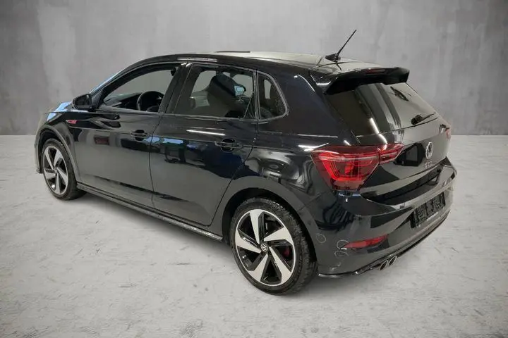 Volkswagen Polo GTI noire vue 3/4 arrière droit, jantes alliage 17 pouces et double sortie d'échappement sport.