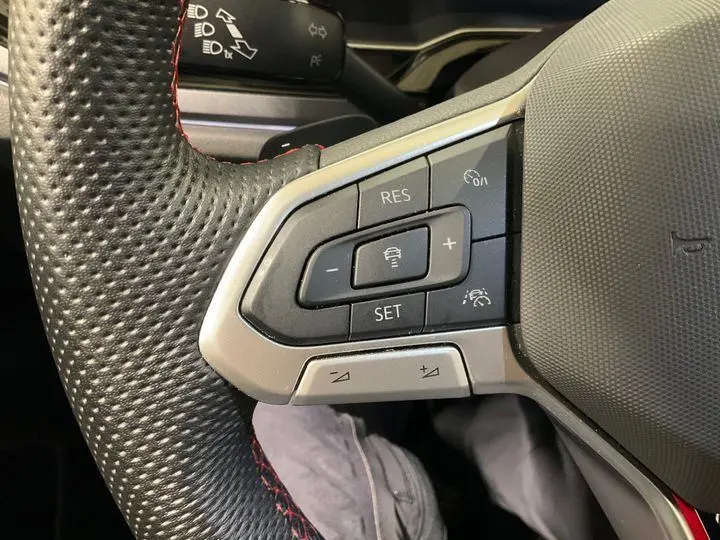 Gros plan sur le côté gauche du volant sport noir perforé avec surpiqûres rouges du Volkswagen Polo GTI 2024.