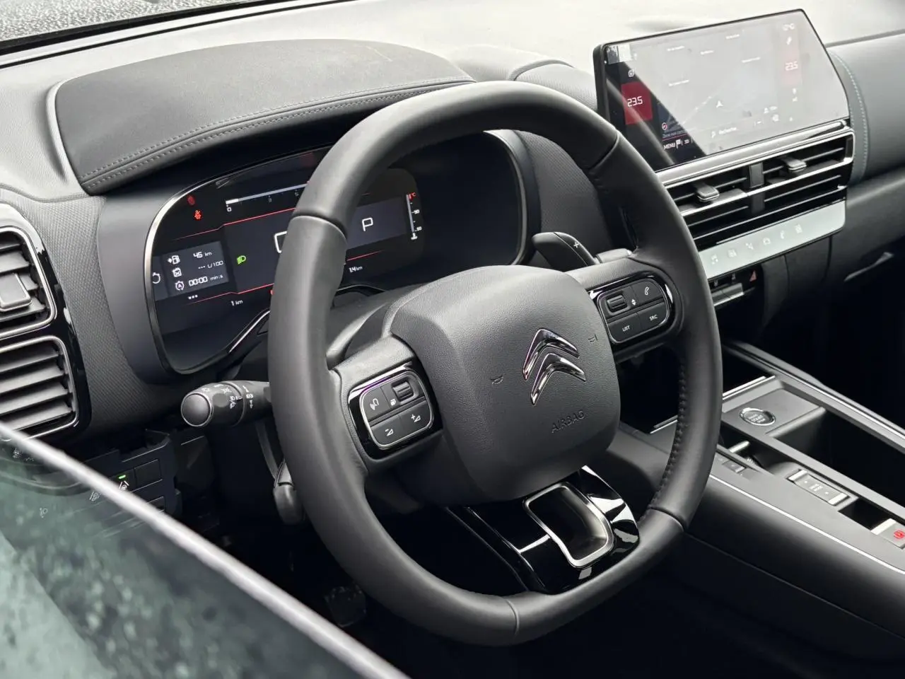 Vue intérieure du poste de conduite du Citroën C5 Aircross 2025, volant cuir noir et écran tactile central.