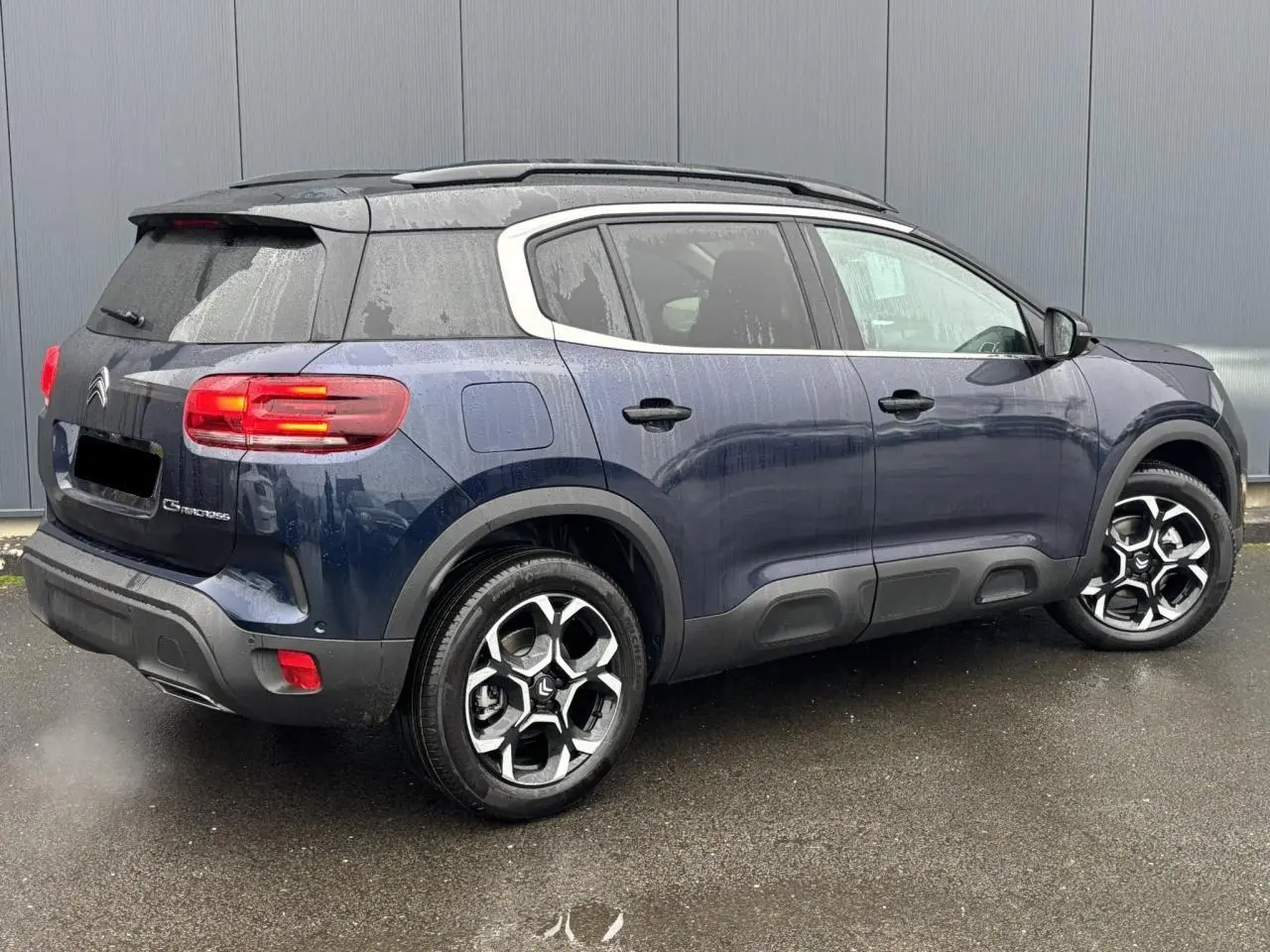 Vue 3/4 arrière droite du Citroën C5 Aircross bleu Eclipse avec jantes alliage bi-ton et toit noir.