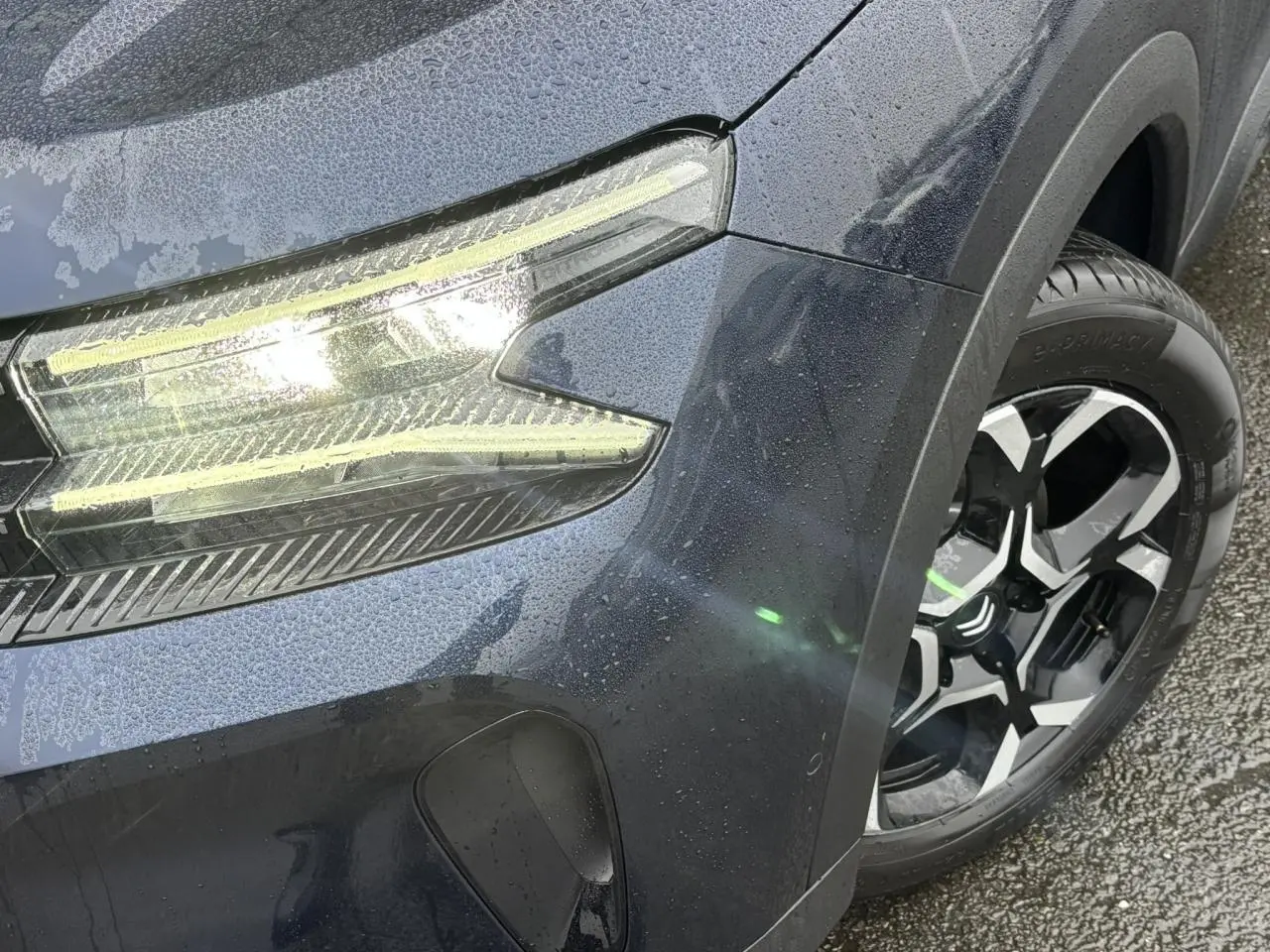 Gros plan sur l'avant droit bleu Eclipse du Citroën C5 Aircross 2025, mettant en valeur le phare LED et la jante alliage 18'' bi-ton.