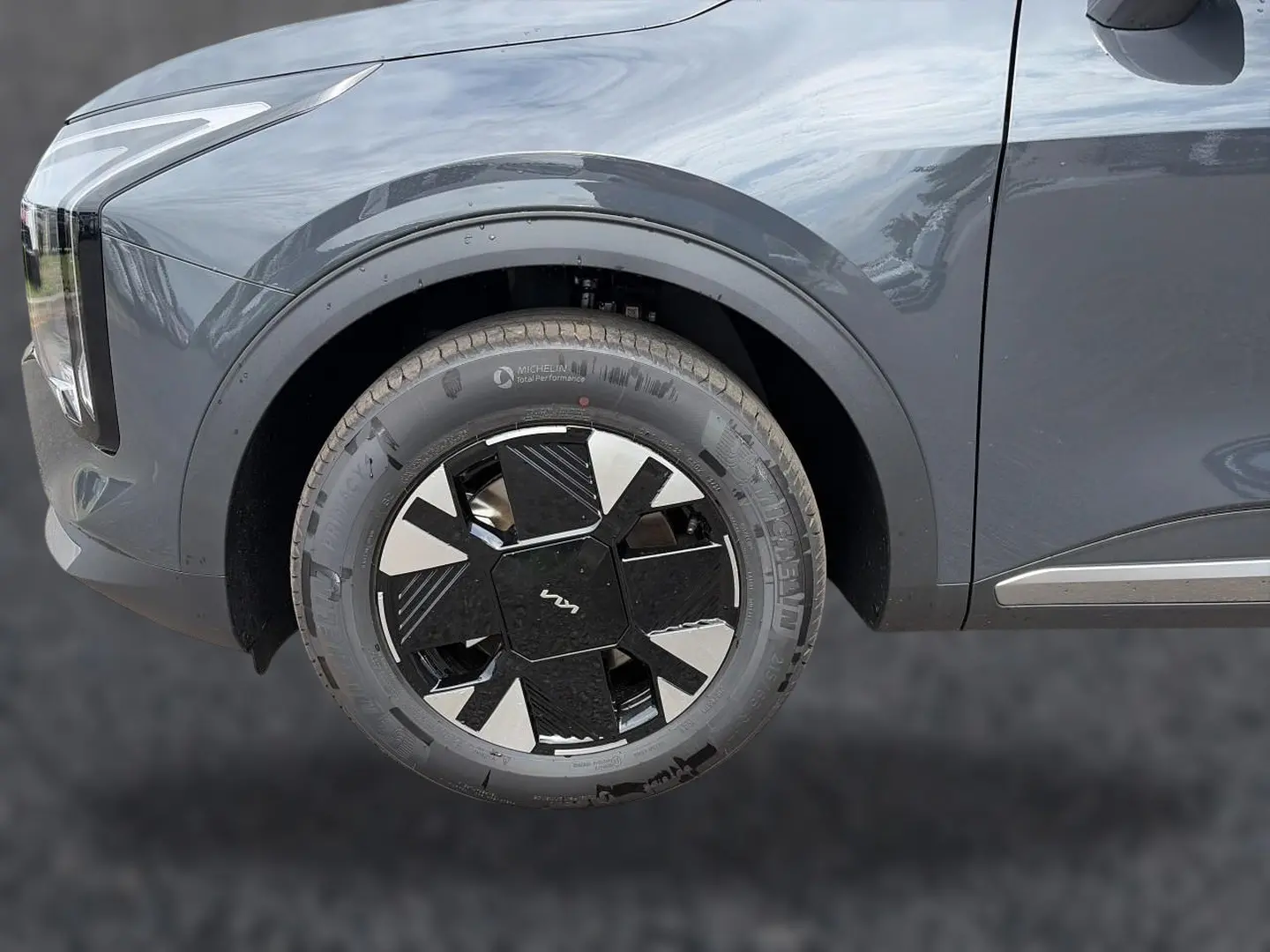 Gros plan sur la roue avant gauche du KIA Sportage gris eclipse, mettant en valeur la jante alu 17 pouces au design moderne.