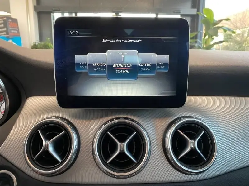 Écran central tactile du Mercedes GLA 200 Sensation 2017 montrant la radio, avec trois aérateurs ronds en dessous.
