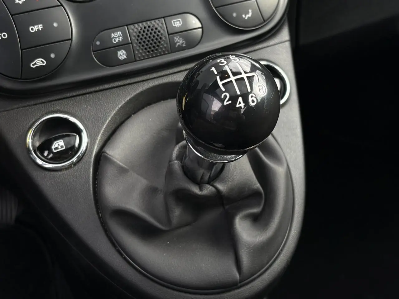 Gros plan sur le levier de vitesses manuel noir dans l’habitacle de la Fiat 500 Hybrid 2024, avec commandes proches.