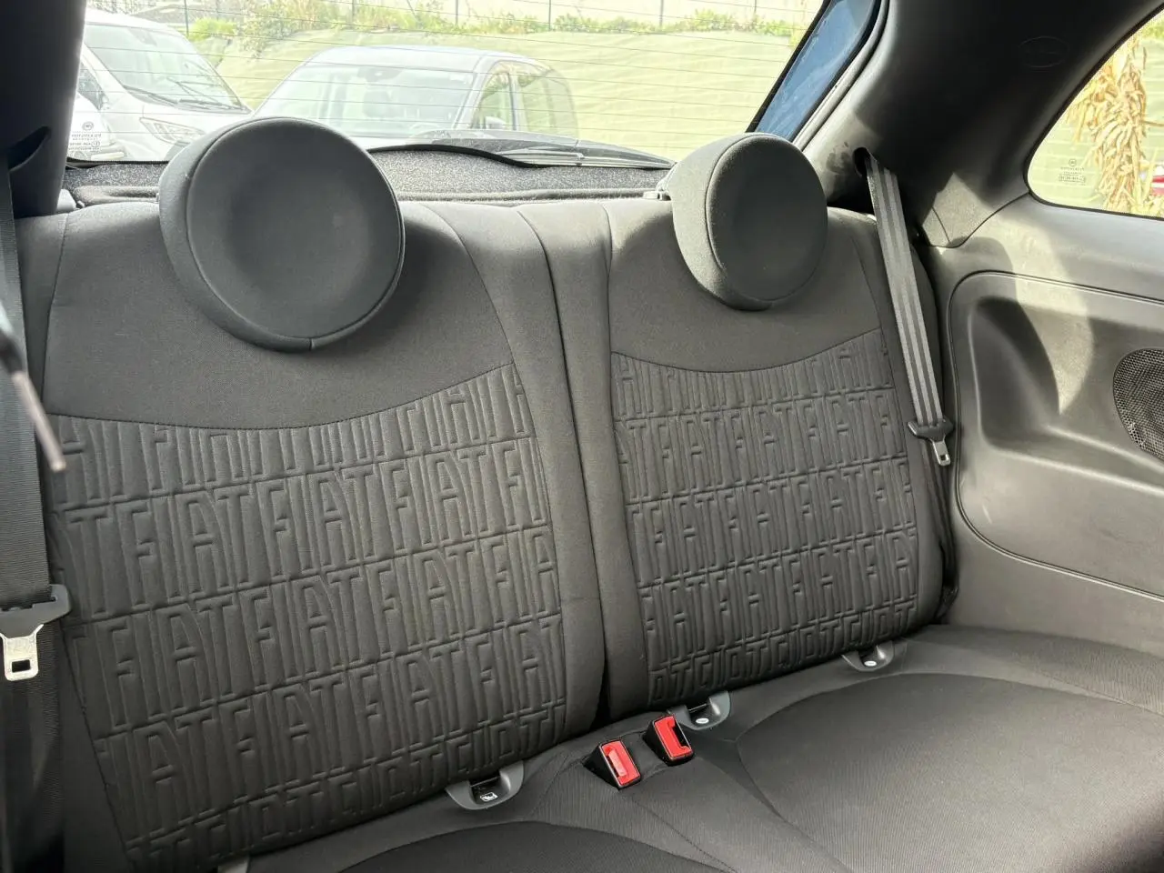 Vue intérieure sur la banquette arrière noire avec motif FIAT embossé, ceintures et appuie-têtes ronds visibles.