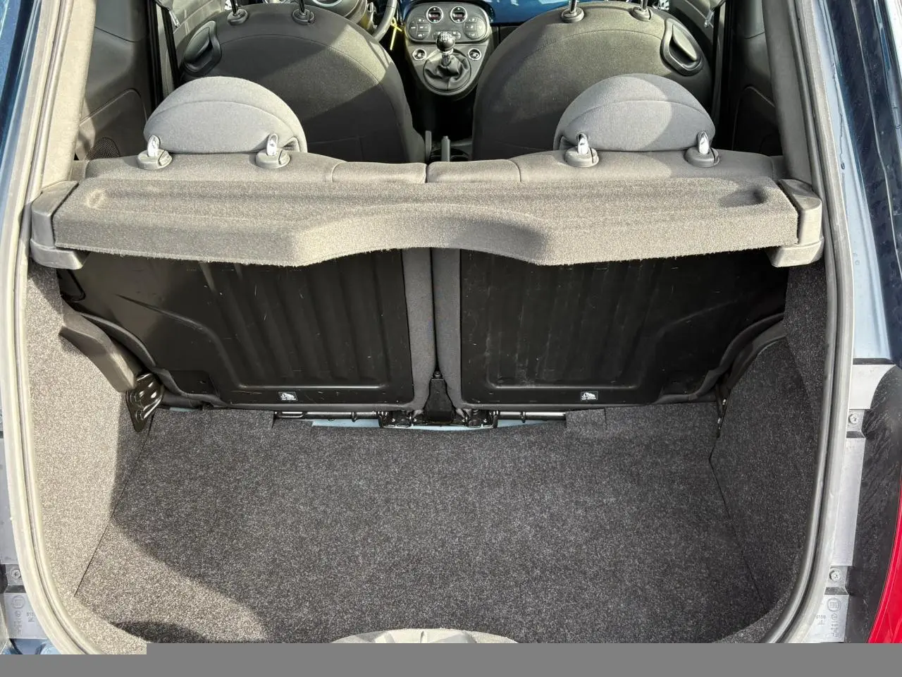 Vue du coffre ouvert d'une Fiat 500 Hybrid 70 bleu Dipinto, montrant l'intérieur et les dossiers des sièges arrière.