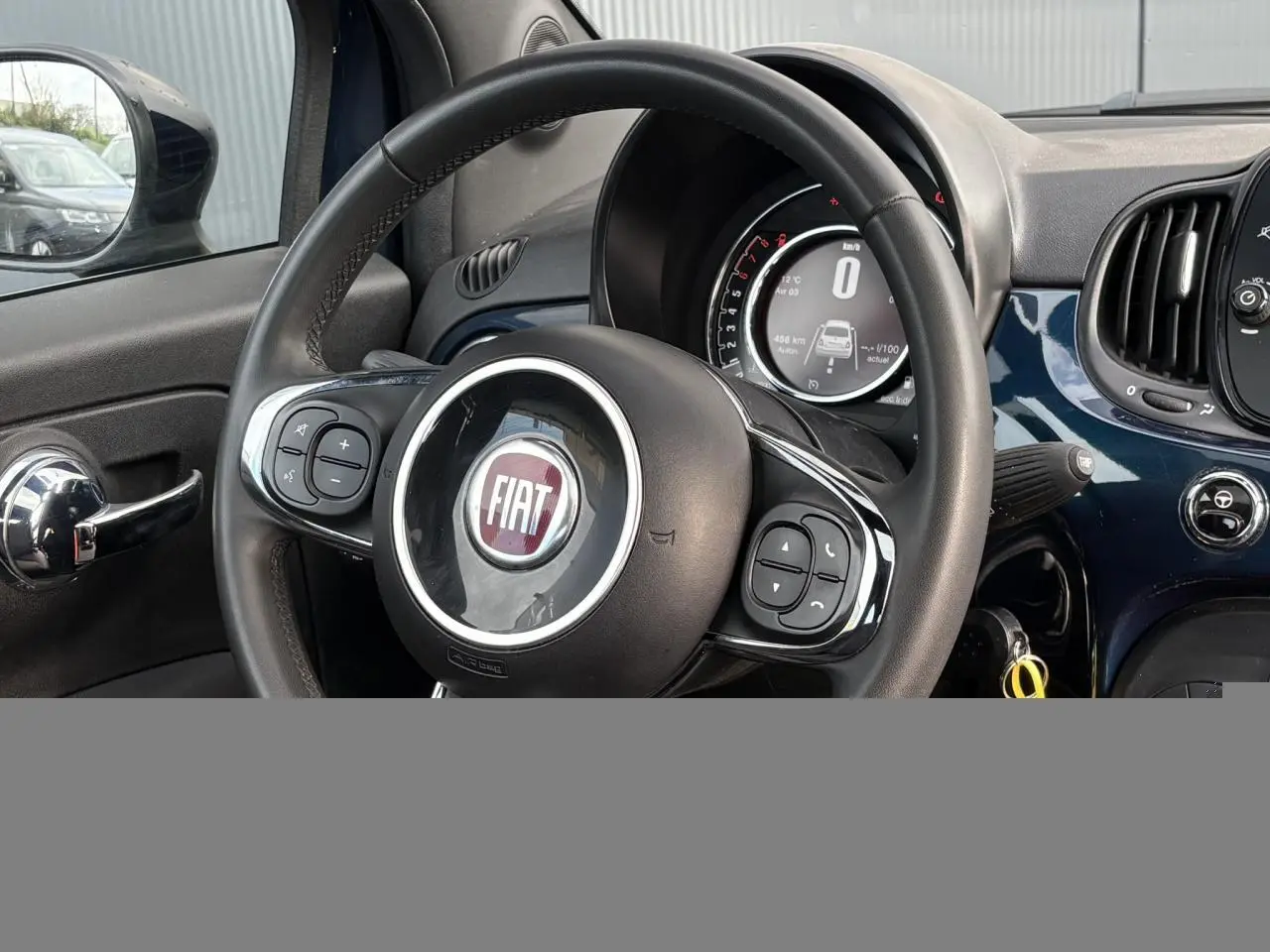 Vue intérieure centrée sur le volant noir et le tableau de bord bleu Dipinto de la Fiat 500 Hybrid 2024.